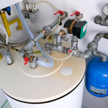 Close-up of a hot water tank system showing valves, pipes, and a blue expansion tank