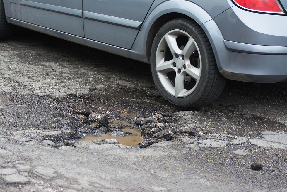 Car parked on cracked asphalt with pothole
