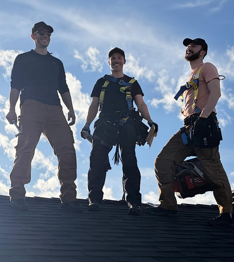 Three construction workers stand confidently on a roof