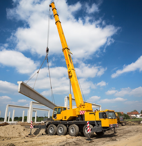 Construction crane hoisting concrete beam at building site