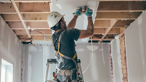 A man is installing fixtures on a ceiling in a residential home