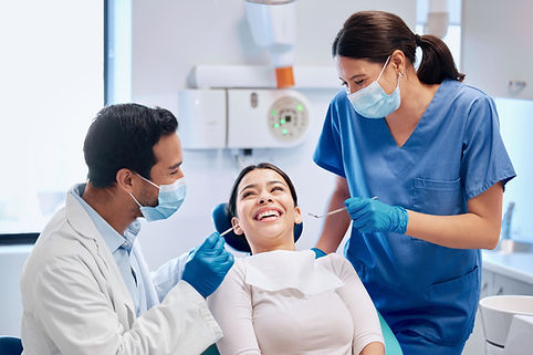 A smiling woman sits in a dentist's chair
