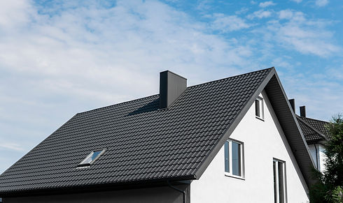 Toit noir à forte pente avec une cheminée sur une maison blanche moderne