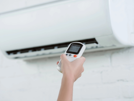 Cropped shot of woman pointing at air conditioner hanging on wall