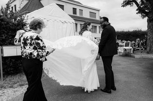 Brautkleid weht im Wind und Mutter hält das Kleid