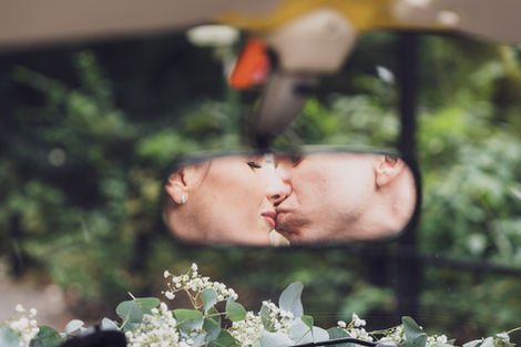 Brautpaar küssen sich vor dem Auto Innenspiegel