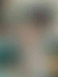 Toddler girl sits on a fall-decorated cream sectional with a dog and books beside her, reading