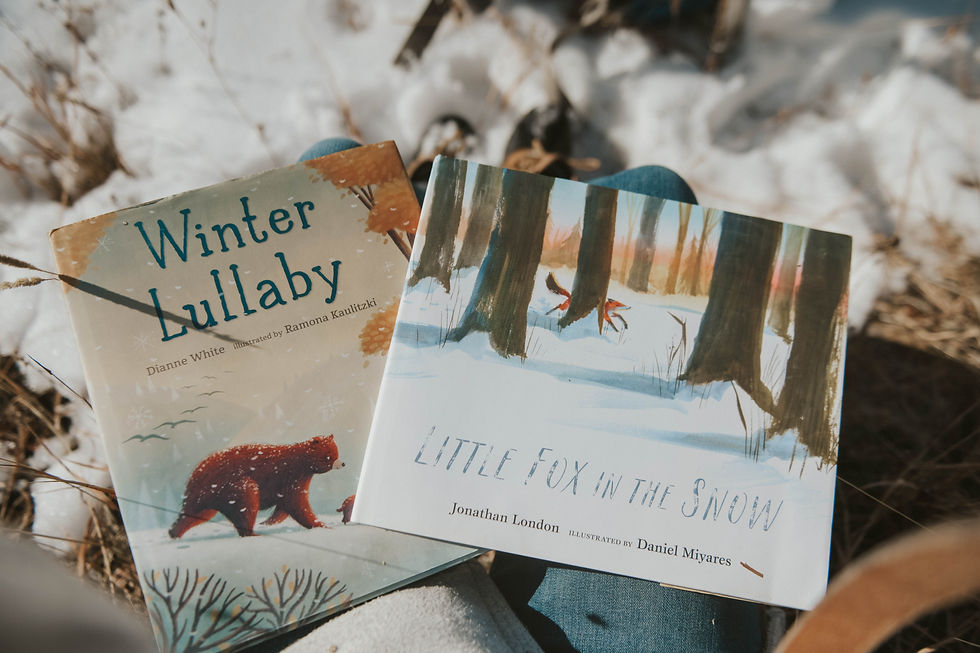 Two children's books, "Winter Lullaby" and "Little Fox in the Snow," rest on a lap in a snowy outdoor setting, evoking a cozy mood.