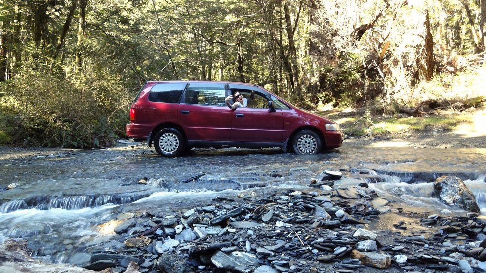 Kati im Auto in einem Flussbett in Neuseeland