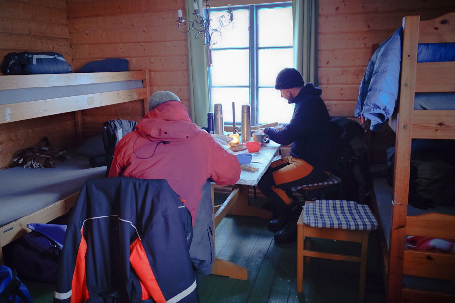 Zwei Menschen sitzen am Tisch in einer Holzhütte