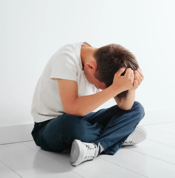 Young boy curled up feeling stressed and anxious