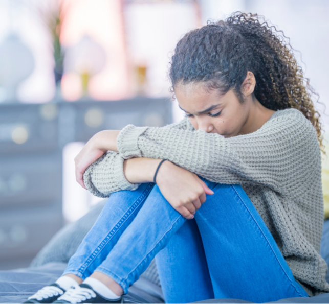 Teen girl sitting on the floor head on her knees depressed