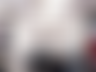 Passengers seated on an airplane with blue seats, screens displaying images. A flight attendant stands in the aisle, blurred background.