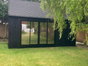 Exterior view of a 5.8m by 3.6m garden gym clad in fully charred larch with shadow gap profile, located in Guildford.