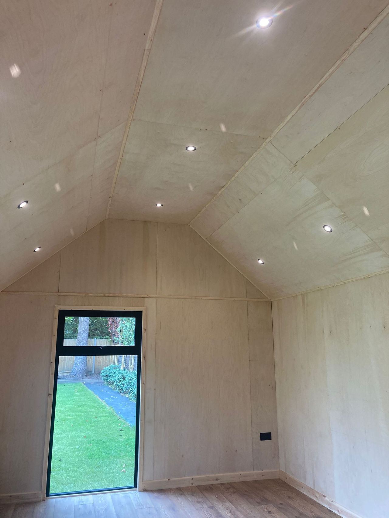 Inside of a garden gym with a vaulted ceiling and walls clad with natural beech bespoke design by Cosy Garden Rooms