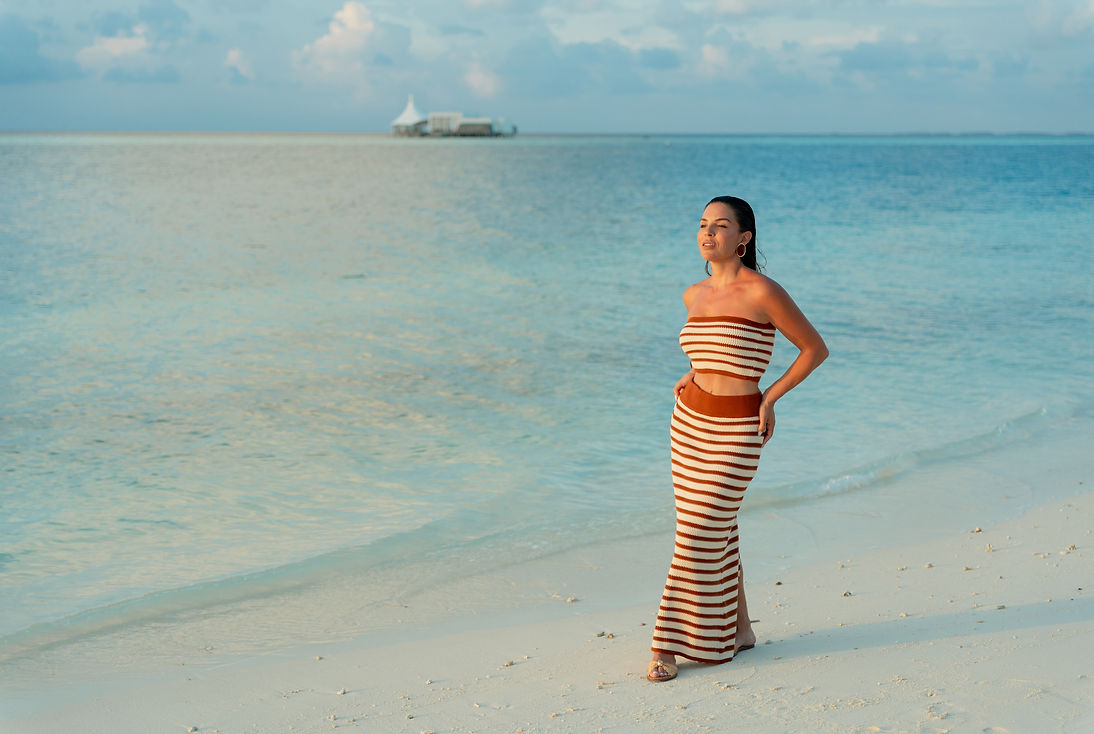 Woman in striped dress on a tropical beach travel scene.