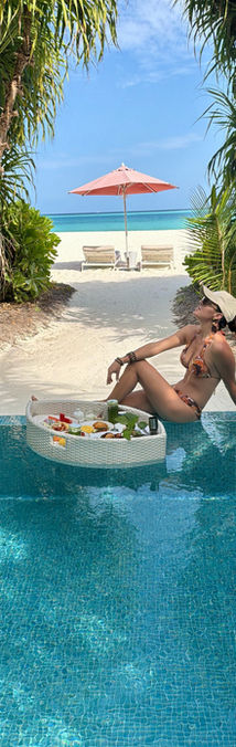 Woman enjoying a floating breakfast in a tropical pool.