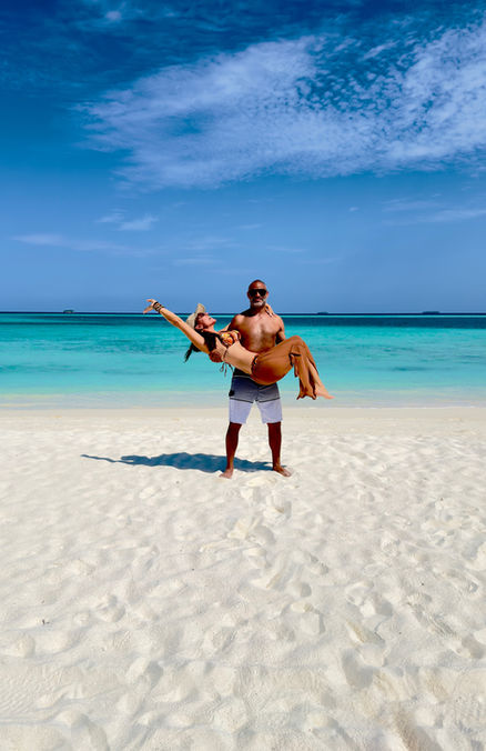 Man carrying a woman on a tropical beach with white sand
