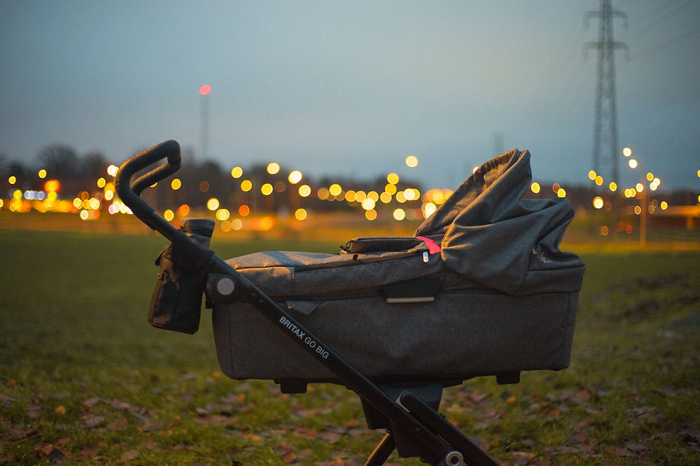 Luxury stroller outside in the evening with lights in the background.