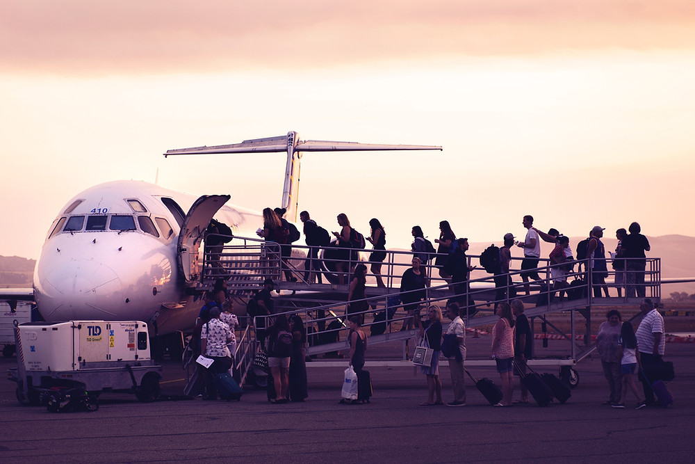 People boarding a white plane from the tarmac.