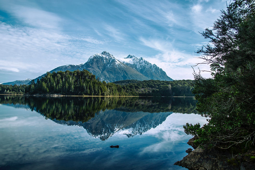 Reflective surface of a lake in Argentina's Lakes District, reflecting a snow-capped mountain.