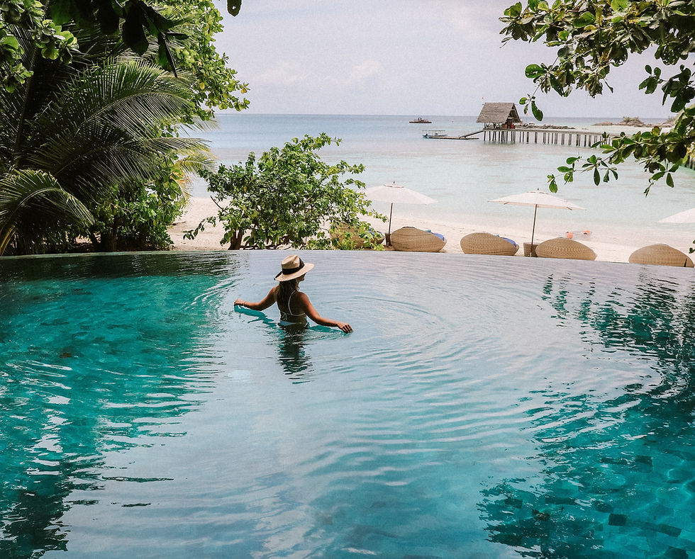 Woman in a sun hat in a pool overlooking the Caribbean during her babymoon in Costa Rica.