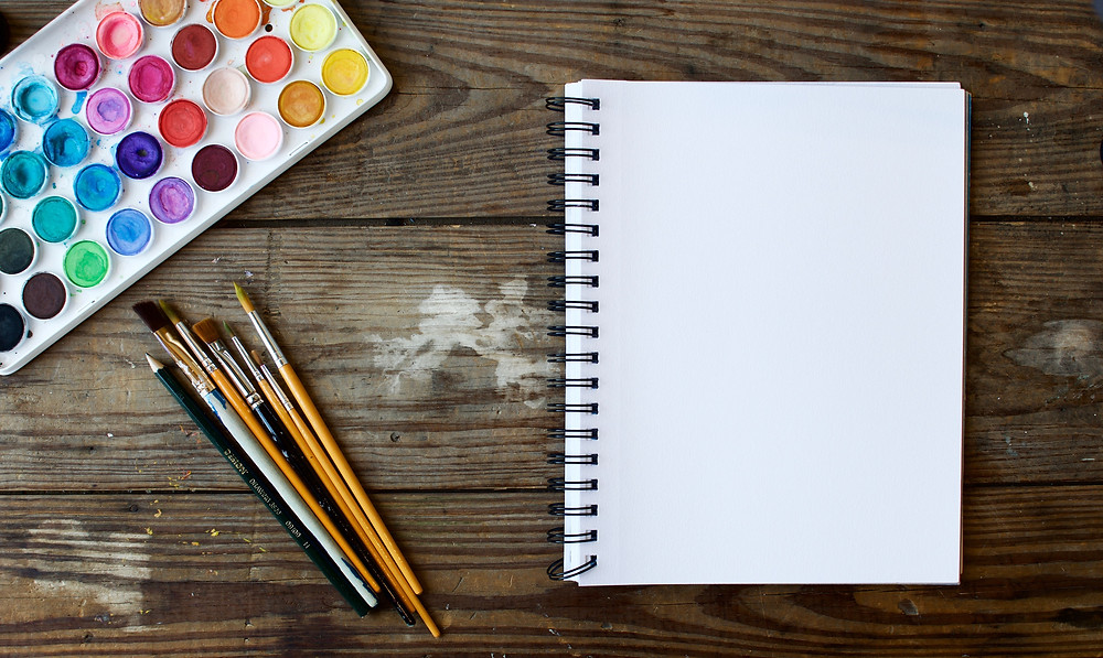 Paints, paper and brushes used to paint images from a volunteer tourism trip