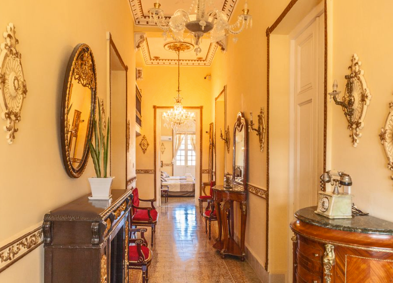 The elegant yellow, gold and wooden hallway of the La Villa Teresa casa particular in Havana. This is best budget accommodations in the city.