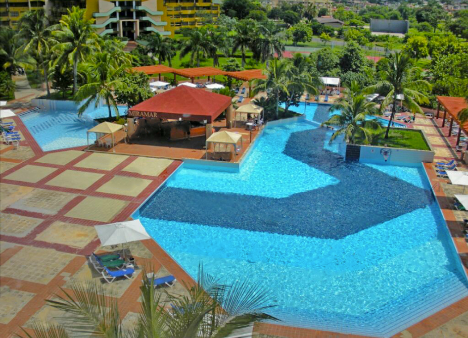 Large blue-tiled pools beside the red and beige patio at Memories Miramar Habana in Cuba.