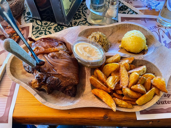 Wooden platter with pork knuckle, roasted potatoes