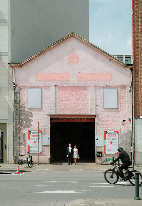 Wedding couple standing in the entrance of an urban building in Brussels, photographed in a documentary style.