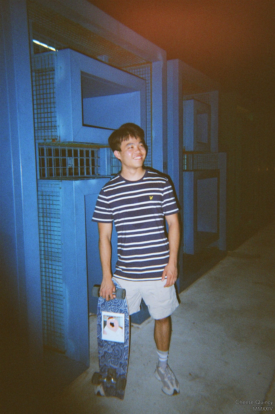 Boy holding a skateboard with Peter Griffin's face and blue Japanese pattern on it, smiling happily