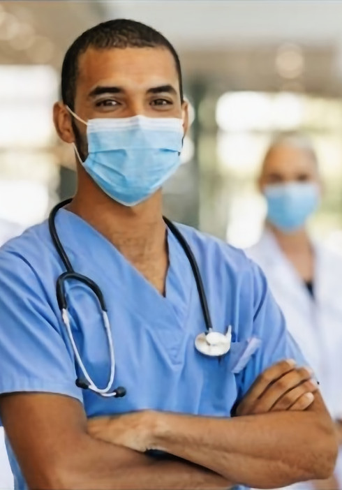 Nurse looking at a camera with nurses and doctors behind him