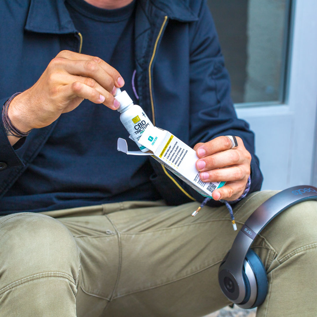 guy taking a tincture bottle out of its box