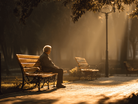 Persona mayor sentada en un parque con expresión de melancolía que evoca la idea de "soledad no deseada"