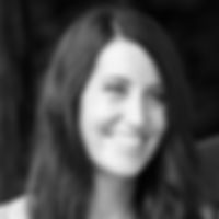 Jennifer Wilson 1985-2024 smiling warmly in black-and-white portrait. She's in a natural setting, with long dark hair and a joyful expression.