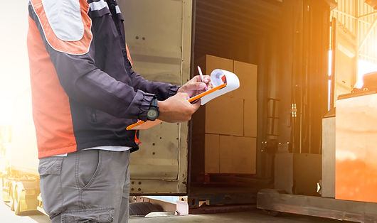 A man filling out some documentation by a loaded truck.