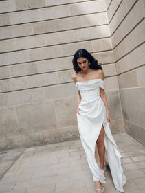 The Sandra gown, featuring beautifully draped details throughout, evokes the feeling of an ancient Greek statue of a goddess. Striking in her simplicity, yet thoughtfully constructed with pleated bodice and sleeves, corset details, and a sultry slit.