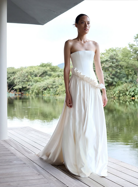 Ruffling the sartorial status quo in Lotus. Introducing a new and luxurious creamy silk satin, Lotus features a modern straight neckline, structured, drop waist bodice and an asymmetric a-line skirt with a high-impact gather. For the fashion-forward amongst us, Lotus boasts a unique a ruffle detail - optional but highly recommended.

COMING SOON