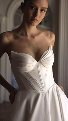 Dove — smooth detailed corset base minimalist bridal gown with heart-shaped neckline and wing-shaped cups. The skirt is elongated by a simple medium length trail.