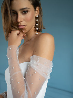 SALE DRESS
The Alexandra gown is thoroughly modern, with just a touch of whimsy.
The fit and flare silhouette, cut in our soft stretch crepe fabric flatters your every curve.
An empire bodice, sculpted with thoughtful seaming detail is flanked by delicate, sheer long sleeves dotted with lustrous pearls of varying size.
The dramatic cutaway slit adds sultry glamour, and buttons down the back of the cathedral length train add a classic bridal detail.
SALE DRESS Was £1600 Now £995