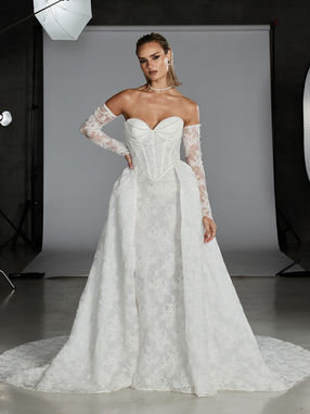 Born of vintage glam inspiration and luxury is our Bardot wedding gown. As iconic and hyper-feminine as her namesake femme fatal.
For the trendsetting brides with glamour in their veins, this gown is fit for the modern starlet.
Corded Chantilly lace adds vintage romance to the style, modernised with a fit-and-flare silhouette. Bardot can be transformed into a fuller, A-line fit with the co-ordinated overskirt.
The bodice is a classic strapless sweetheart neckline, constructed with corset boning for contoured structure. Meeting the figure-hugging skirt at the trending Basque waistline, accentuating the effect of an hourglass figure.
Chic, pearl drape detailing decorates the bust to add subtle drama to the look, while maintaining Bardot’s classic inspiration.
To complete the look and add an additional style, Bardot includes matching illusion lace off-the-shoulder sleeves. Making this a three-in-one gown to take from ceremony, to reception, and through the entire night.
Also available without pearls or in a satin finish
Overskirt sold separately £809
