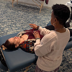 Reiki practitioner performing In Person Reiki Healing on a client lying on a massage table