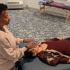 Reiki practitioner performing hands-on healing on a client lying on a table, In Person Reiki Healing