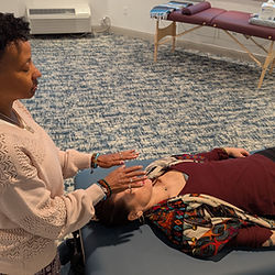 Reiki practitioner performing hands-on healing on a client lying on a table, In Person Reiki Healing