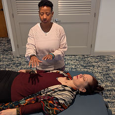 Reiki practitioner performing hands-on healing on a client lying down