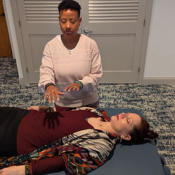 Reiki practitioner performing hands-on healing on a client lying down