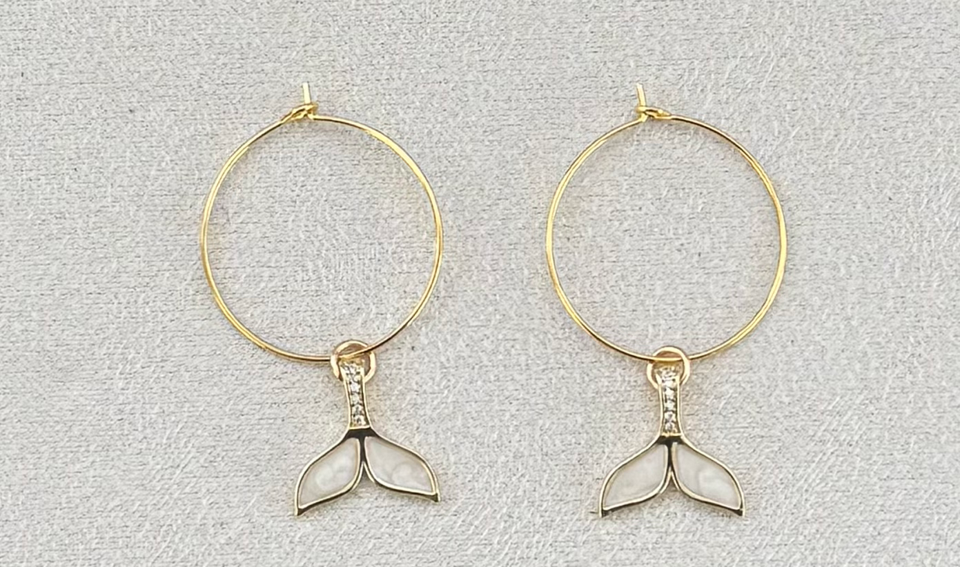 Gold hoop earrings with a white enamel and crystal mermaid tail charm