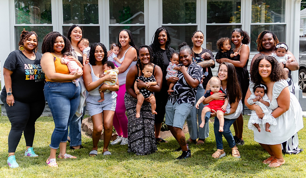 Group of women holding babies outside a house alongside owner TaKiesha