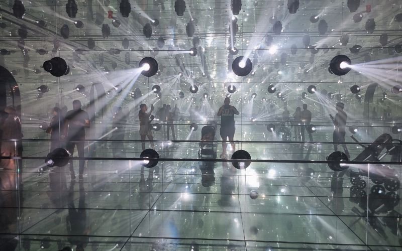 Visitors inside mirror light installation at AYA Universe Dubai with glowing reflections